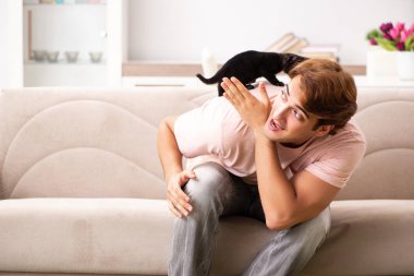 Genç adam evde kedi yavrusuyla oynuyor.