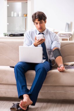 Stres altındaki adam kan basıncını ölçüyor.