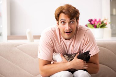 Genç adam evde kedi yavrusuyla oynuyor.
