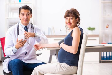 Genç doktor hamile kadınların kan basıncını ölçüyor.