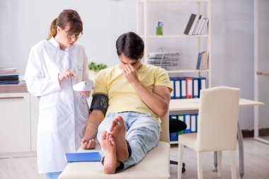 Genç doktor hastaların tansiyonunu ölçüyor.