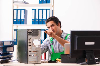 Ofiste bozuk bilgisayarı tamir eden genç bir mühendis. 