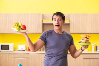 Sağlıklı ve sağlıksız yemek arasında zor bir seçim yapan bir adam.
