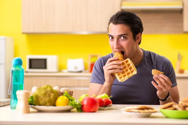 Homem tendo escolha difícil entre alimentos saudáveis e não saudáveis — Fotografia de Stock