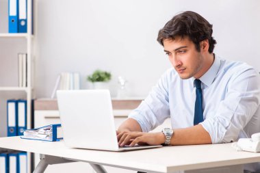 Genç yakışıklı işadamı ofiste çalışıyor.