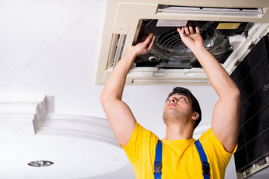 Repairman repairing ceiling air conditioning unit