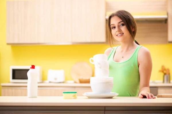 Молодая женщина моет и моет посуду на кухне — стоковое фото