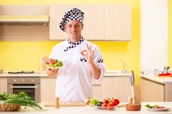 Joven cocinero profesional preparando ensalada en la cocina — Foto de Stock