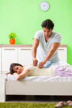 Adam yatak odasında karısına masaj yapıyor. 