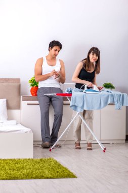 Genç kadın kocası için ütü yapıyor.