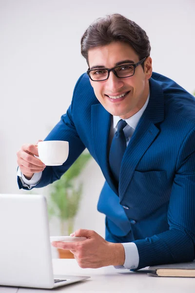 Junger schöner Geschäftsmann trinkt Kaffee im Büro — Stockfoto