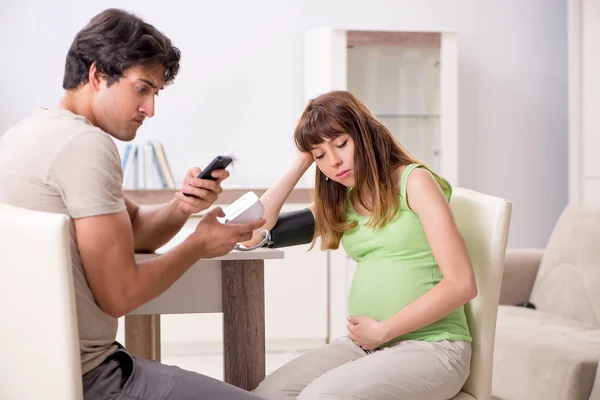 Husband checking pregnant wifes blood pressure