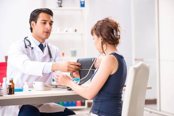 Молодий лікар перевіряє жіночий кров'яний тиск — стокове фото