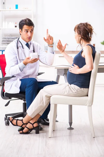 Giovane medico che controlla la pressione sanguigna delle donne incinte — Foto Stock