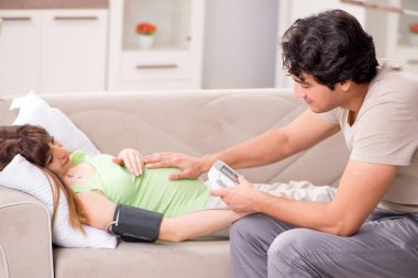 Koca hamile eşlerin tansiyonunu ölçüyor.