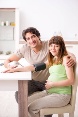 Koca hamile eşlerin tansiyonunu ölçüyor.