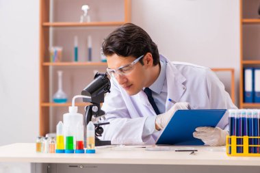 Genç yakışıklı biyokimyacı laboratuvarda çalışıyor.  