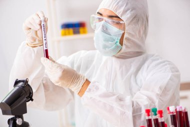 Genç yakışıklı laboratuvar asistanı hastanede kan örnekleri test ediyor. 