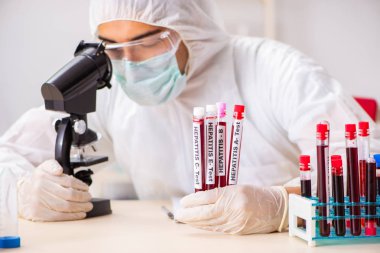 Genç yakışıklı laboratuvar asistanı hastanede kan örnekleri test ediyor. 