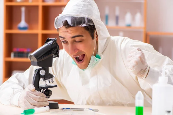 Mladý biochemik v ochranném obleku pracuje v laboratoři — Stock fotografie