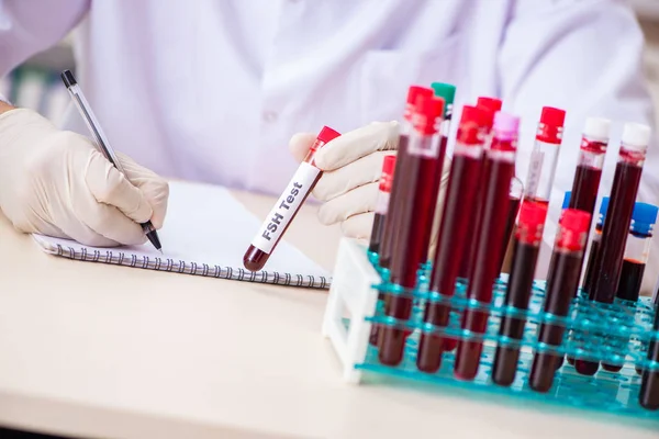 Asistente de laboratorio joven guapo analizando muestras de sangre en el hospital — Foto de Stock