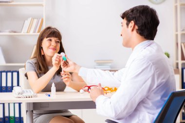 Genç bir kadın, erkek doktor göz doktorunu hastanede ziyaret ediyor.