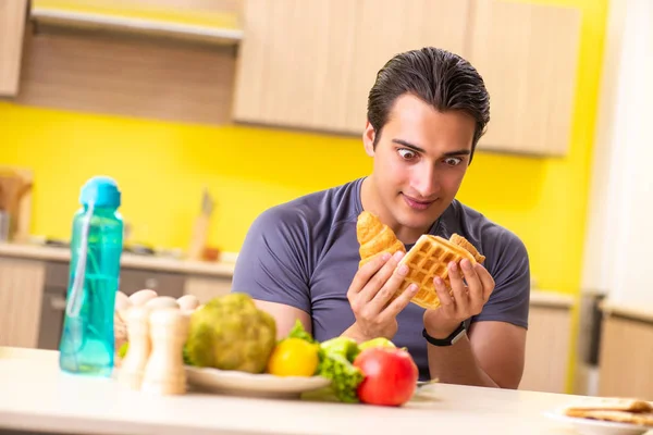 Man having hard choice between healthy and unhealthy food