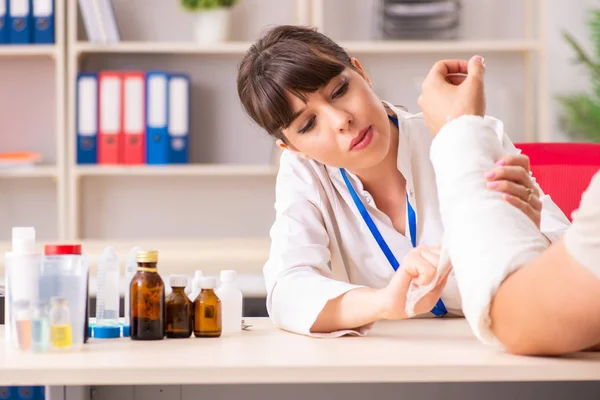 Young man with bandaged arm visiting female doctor traumatologis — Stock Photo, Image