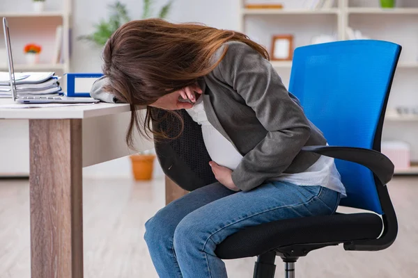 Беременная женщина борется с болью в офисе — стоковое фото