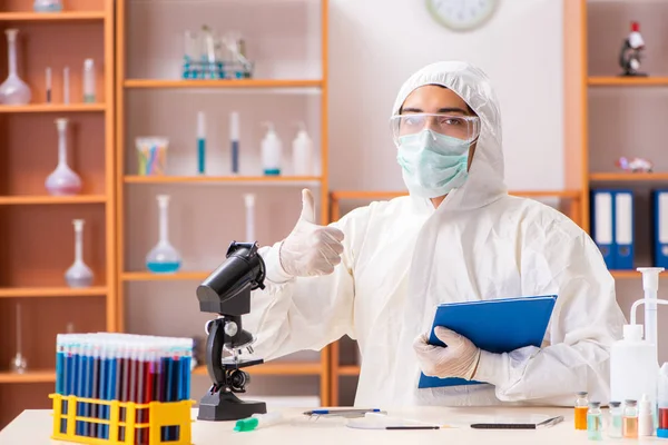 Joven bioquímico con traje protector trabajando en el laboratorio —  Fotos de Stock