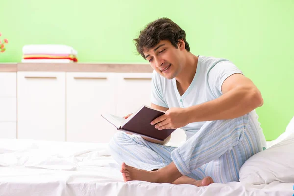 Giovane studente bello libro di lettura nel letto — Foto Stock