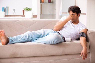 Evde kan basıncını ölçen genç bir adam.