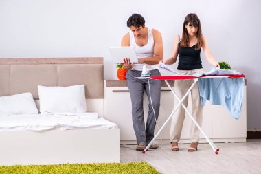 Genç kadın kocası için ütü yapıyor.