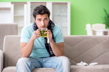 Evde hastalıktan muzdarip genç yakışıklı bir adam. 