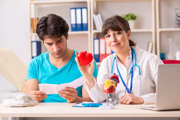 Jeune homme visitant femme médecin cardiologue — Photo