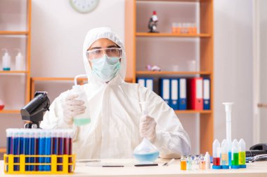 Laboratuvarda çalışan koruyucu elbise giyen genç bir biyokimyacı.