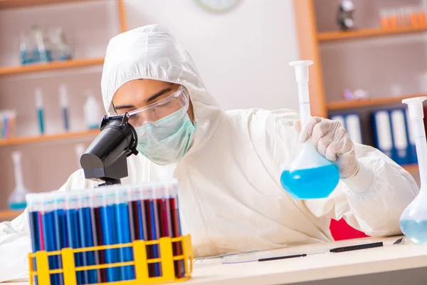 Młody biochemik w kombinezonie ochronnym pracujący w laboratorium — Zdjęcie stockowe