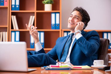 Genç yakışıklı işadamı ofiste çalışıyor.