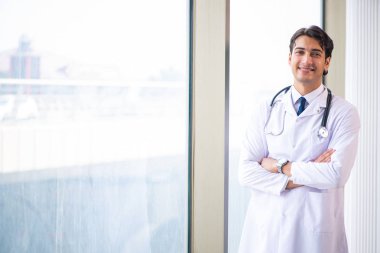 Genç yakışıklı doktor pencerede duruyor. 