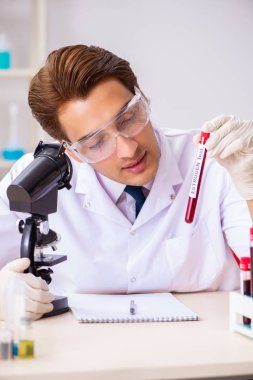 Genç yakışıklı laboratuvar asistanı hastanede kan örnekleri test ediyor. 