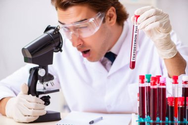 Genç yakışıklı laboratuvar asistanı hastanede kan örnekleri test ediyor. 