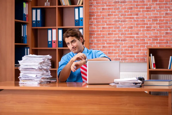 Young employee with excessive work sitting at the office — Stock Photo, Image