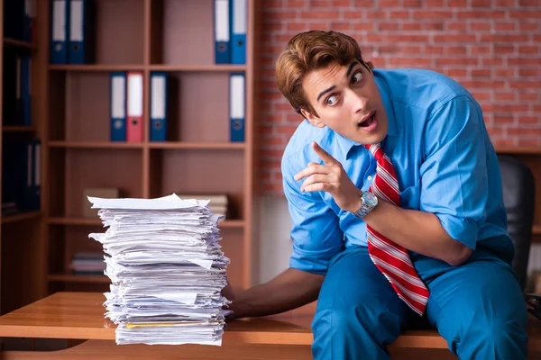 Empleado joven con exceso de trabajo sentado en la oficina — Foto de Stock