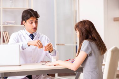 Genç bir kadın, erkek doktor göz doktorunu hastanede ziyaret ediyor.