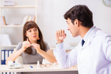 Genç bir kadın, erkek doktor göz doktorunu hastanede ziyaret ediyor.