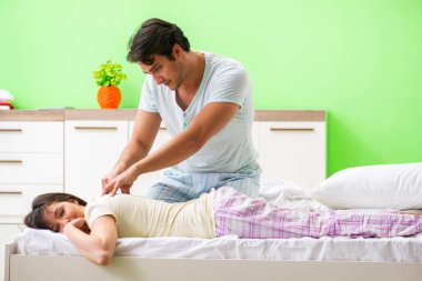 Adam yatak odasında karısına masaj yapıyor. 