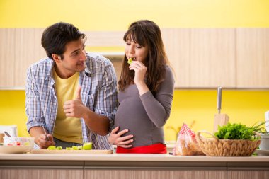 Erkek ve hamile kadın mutfakta salata hazırlıyorlar. 