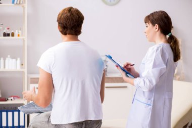 Erkek hasta genç bayan doktor kayropraktik uzmanını ziyaret ediyor. 