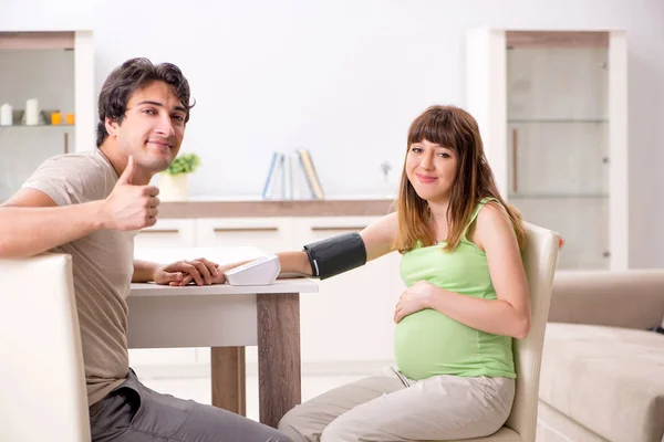 Ehemann überprüft Blutdruck schwangerer Frauen — Stockfoto