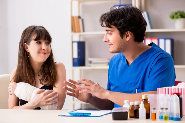 Young woman with bandaged arm visiting male doctor traumotologis — Stock Photo, Image